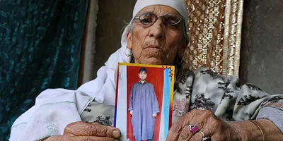 Naseer Ahmad’s grandmother holding his picture. Photo: Kamran Yousuf 