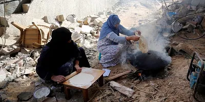 Women bake bread surrounded by destroyed buildings in Khan Yunis, Gaza during the recent humanitarian pause. Photo: UNRWA/Ashraf Amra.